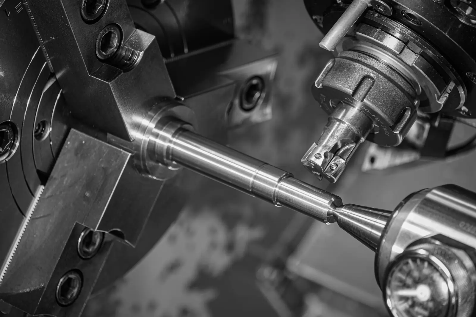 A metal rod turns in a lathe while a cutting tool shapes it